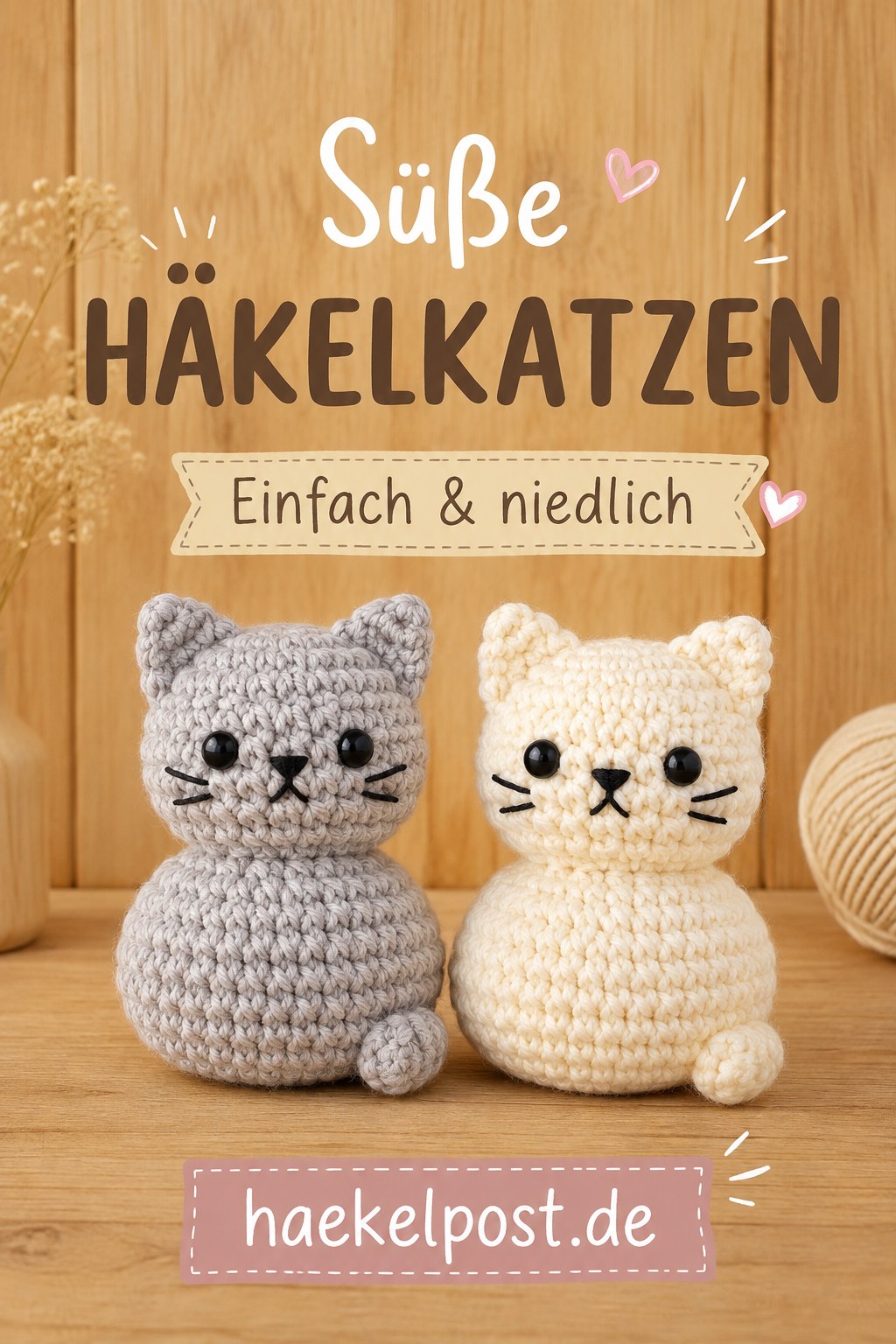Zwei runde gehäkelte Mini-Katzen in Grau und Creme stehen nebeneinander auf einem Holzbrett vor Wollknäuel.