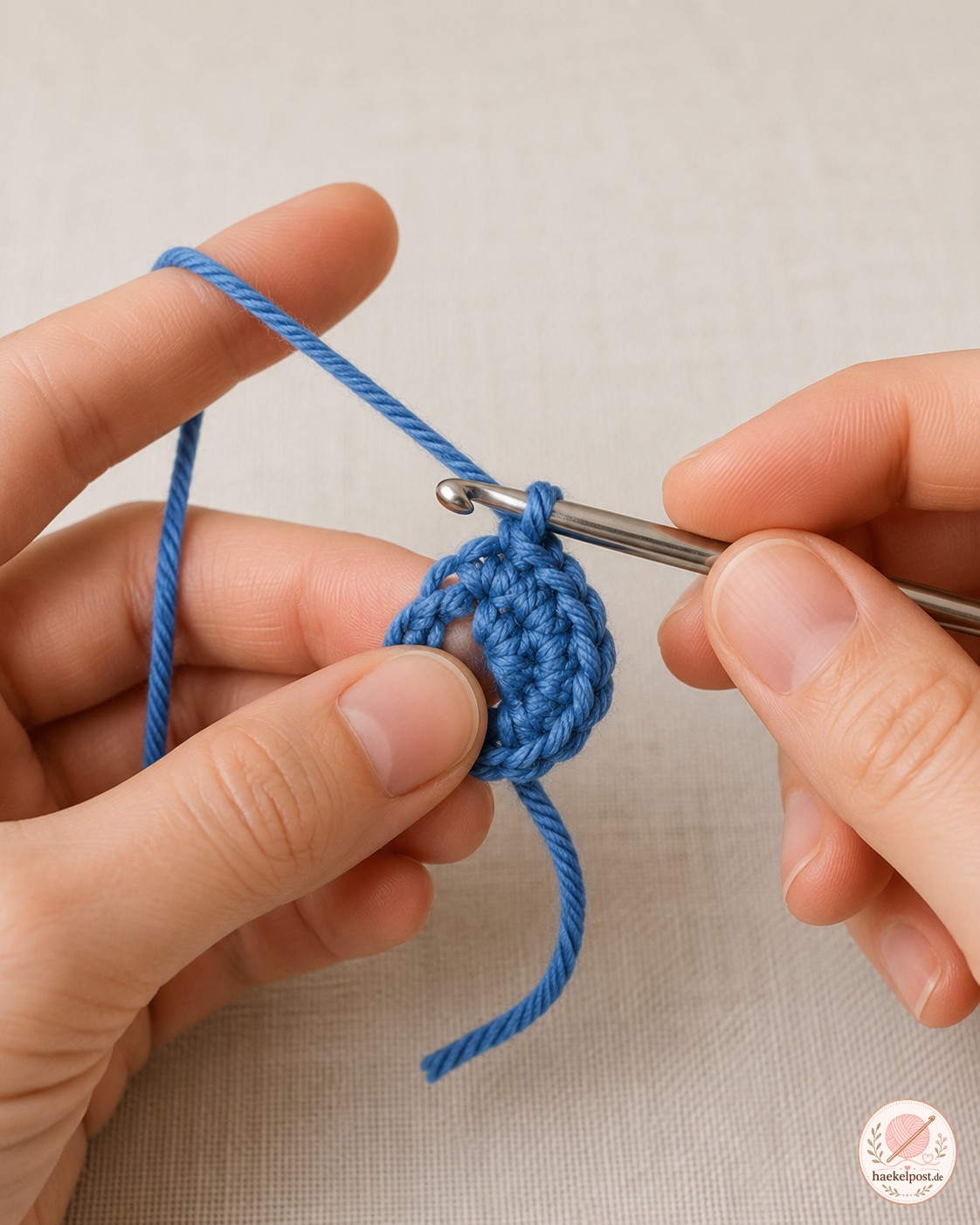 Hände formen einen Fadenring in Blau als ersten Schritt beim Wal häkeln für die Schwanzflosse.